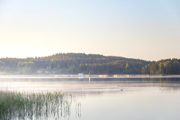 A lake with a foggy morning sky and a small town in the background