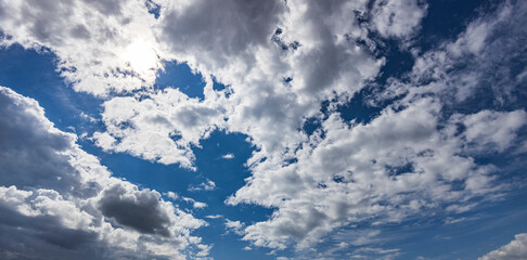 Fluffy clouds drift across a vivid blue sky, casting shadows over the serene landscape, creating a...