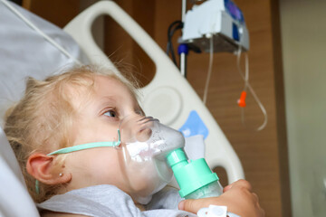 Little girl in hospital breathing through oxygen mask. Health concept.