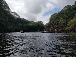 A beautiful shot of a lake with a cuddy boat sailing in the middle and rocky mountains on both sides
