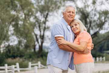 Obraz premium Happy Senior Couple Embracing Outdoors in Nature During a Summer Day