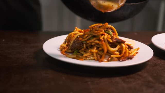 Сlose-up of delicious lagman lying on white plates noodles with beef and vegetables served dish. 