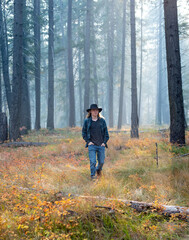 Fototapeta premium young man, wearing flannel shirt and jeans, walking though autumn forest