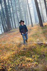 Fototapeta premium young man, wearing flannel shirt and jeans, walking though autumn forest