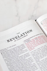Obraz premium Revelation of God Jesus Christ in open holy bible book placed on white marble background. Studying Christian Scripture, end time prophecy, biblical concept.