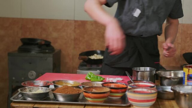 Cutting semi-bitter green pepper into large pieces on a cutting board by the hands of a chef to prepare an Asian dish with many different spices and seasonings.
