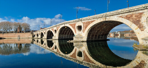 Pont Neuf Reflected in the Garonne River at Sunrise, Bathed in Golden Light with a Clear Blue Sky, Toulouse