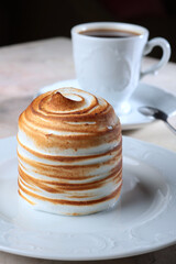 Sweet marshmallows or meringue with a honey layer. Dessert on a white plate. A cup of coffee. The concept of food and drinks.