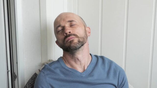 A man sitting in a chair is stretching his stiff neck