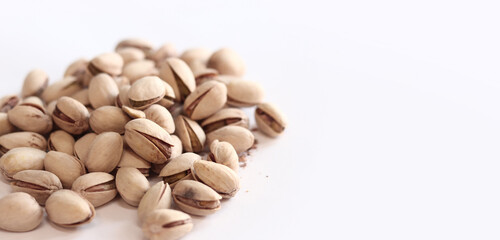 Pistachios on a white background. A handful of dry salted pistachios on a light background, selective focus. Pistachio with shell. Close-up