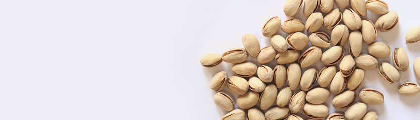 Pistachios on a white background. A handful of dry salted pistachios on a light background, selective focus. Pistachio with shell. Close-up