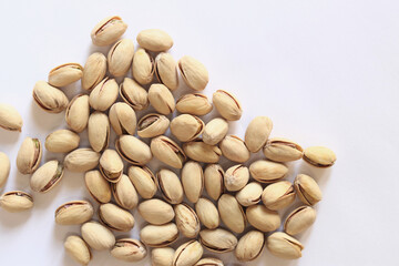 Pistachios on a white background. A handful of dry salted pistachios on a light background, selective focus. Pistachio with shell. Close-up