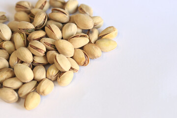 Pistachios on a white background. A handful of dry salted pistachios on a light background, selective focus. Pistachio with shell. Close-up