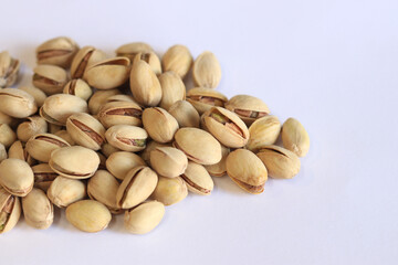 Pistachios on a white background. A handful of dry salted pistachios on a light background, selective focus. Pistachio with shell. Close-up