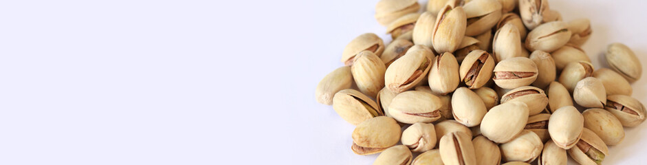 Pistachios on a white background. A handful of dry salted pistachios on a light background, selective focus. Pistachio with shell. Close-up