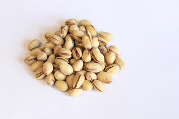 Pistachios on a white background. A handful of dry salted pistachios on a light background, selective focus. Pistachio with shell. Close-up