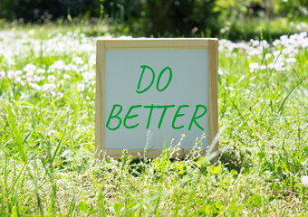 Do Better symbol. Do Better white chalk blackboard. Beautiful meadow background. Business and Do...