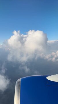 looking out airplane window at the clouds over the engine and wing in flight