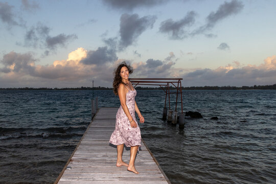 Beautiful woman walking on a boat dock or pier in the evening at the island of Bora Bora. 