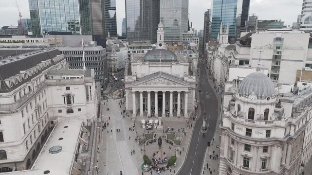 Drone aerial shot flying back away from the Bank of England in Central London, with the high rise skyscrapers in the background on a normal cloudy day