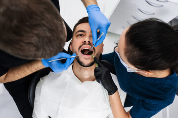 Initial examination of the patients oral cavity by dentist. Handsome man is having preventive...