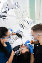Assistant helps dentist to prepare teeth before treatment using airflow instrument. Airflow teeth...