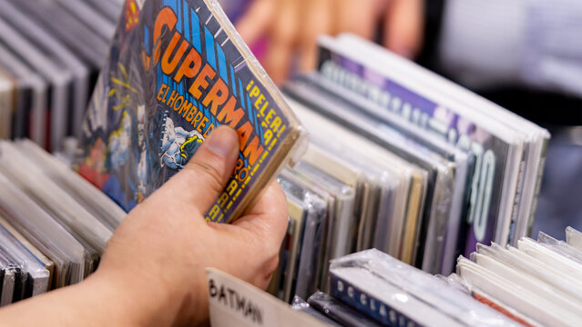 9th Comic Con Convention In GUAYAQUIL, ECUADOR - AUG 04, 2024 - Woman's hand selecting comics from a box. Comic shop with many copies. Superman comic book.