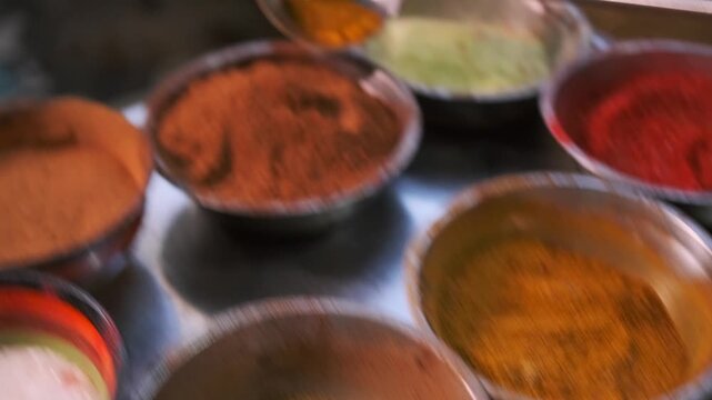 A steel ladle collects seasonings and spices paprika turmeric salt pepper to prepare an oriental dish with a spicy taste, close-up.