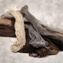 textured stylish old paper background, square, with cotton embroidery thread hanks in different...