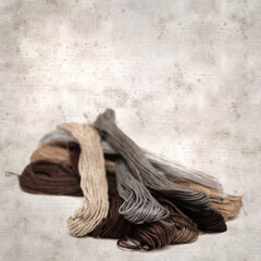 textured stylish old paper background, square, with cotton embroidery thread hanks in different...