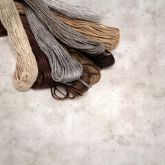 textured stylish old paper background, square, with cotton embroidery thread hanks in different...