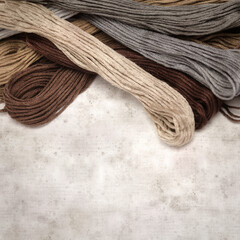 textured stylish old paper background, square, with cotton embroidery thread hanks in different...
