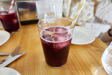 Glass with ice and sangria or a typical Spanish cocktail with red wine and soda called Tinto de Verano, on a wooden table in a restaurant. With a striped paper straw