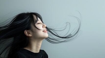 Happy woman with windblown hair smiling joyfully against a simple white background