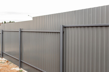 Fototapeta premium Grey corrugated board fence. The reverse side of the fence with posts and lintels. Galvanized profiled sheet