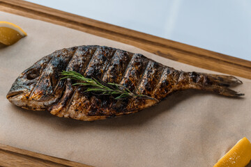 Dorado fish baked with lemon on a barbecue on a wooden board