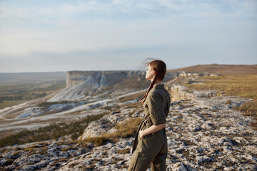 Woman standing on cliff looking over valley below in travel adventure scene with stunning view of...