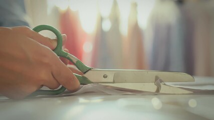 Small business. Beautiful Asian girl professionally uses scissors to cut in fabric store. Steady camera movement modern girl cutting fabric with industrial scissors follows fashion trends, needlewoman