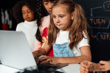 Smart girl in white bib learning about coding robotics technology using laptop in the STEM class....