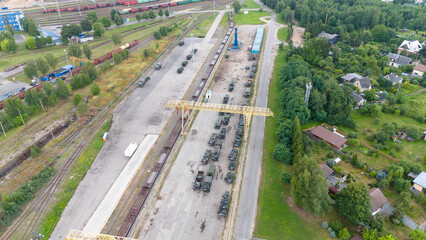 Drone photography of military convoy at train station during summer day