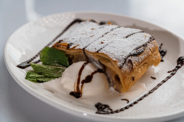 Dessert strudel with chocolate and ice cream on a white plate