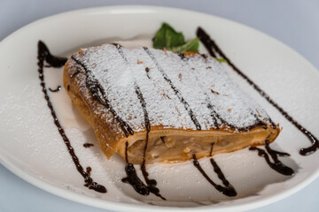 Dessert strudel with chocolate and ice cream on a white plate