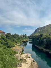 Naklejka premium Neretva River in Mostar with Trees and Rooftops in Background