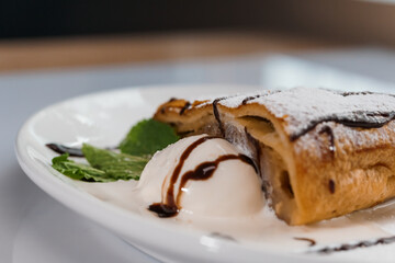 Dessert strudel with chocolate and ice cream on a white plate