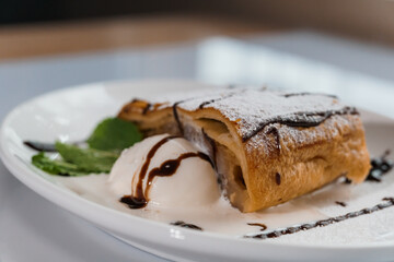 Dessert strudel with chocolate and ice cream on a white plate