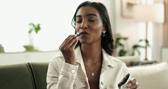 Home, relax and girl eating dark chocolate for taste and enjoy snack with cocoa flavor or smile. Apartment, female person or Indian woman with sweet treat and sugar craving with comfort food or candy