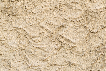 Yellow plaster on the wall in rough style, sandy texture, used as an exterior facade finish. texture of building materials