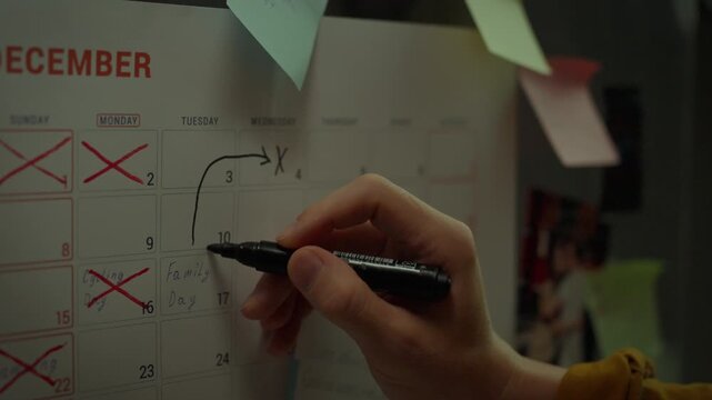 Close up of Asian man's hand writing note in weekly planner with marker. Setting and achieving goals. Weekly schedule planning calendar. Sticky note for posting. Marking with marker to move tasks