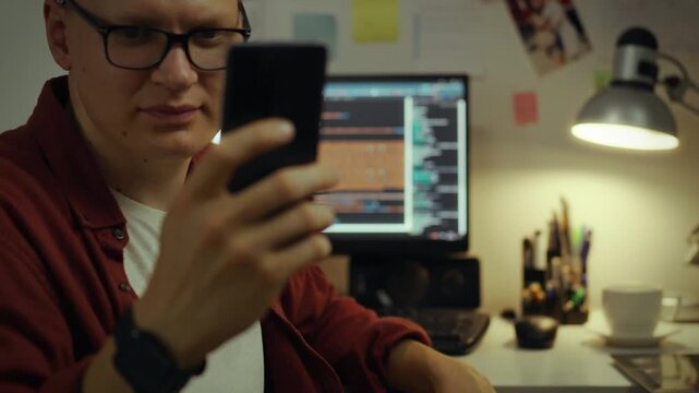 IT specialist. European guy analyzes data streams with a smartphone at work. In slow motion, a remote access worker operates in an innovation hub, develops a neural network, administrator