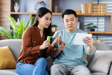 Asian family having online consultation with doctor through video call on tablet. Two people discussing health issues, showing medication and following doctor's advice.